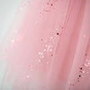Close-up of a light pink tulle fabric with scattered pink, red, and metallic sequins.