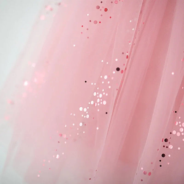 Close-up of a light pink tulle fabric with scattered pink, red, and metallic sequins.