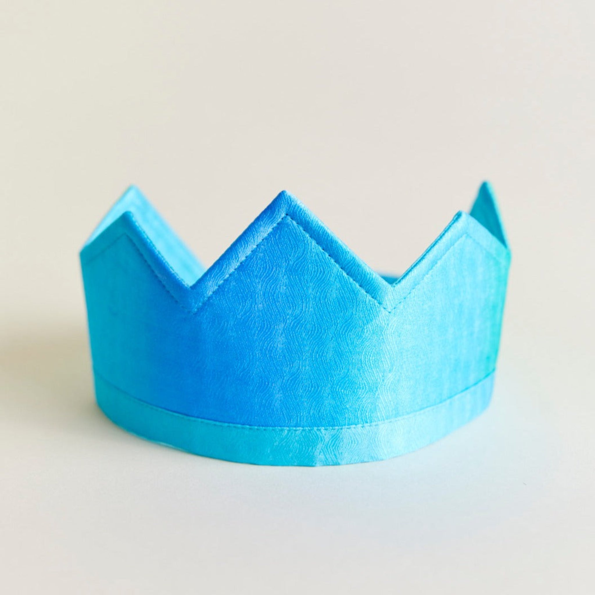Blue paper crown on a light beige background
