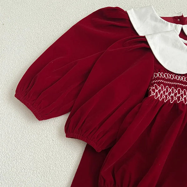 Red dress with white collar and embroidery on a light background