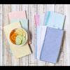 Set of eight multicolor seersucker cloth napkins fanned out on a table, showing vibrant colors and textured weave