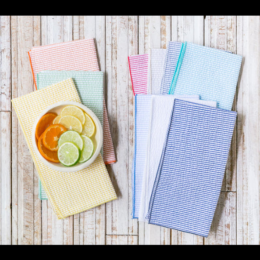 Set of eight multicolor seersucker cloth napkins fanned out on a table, showing vibrant colors and textured weave