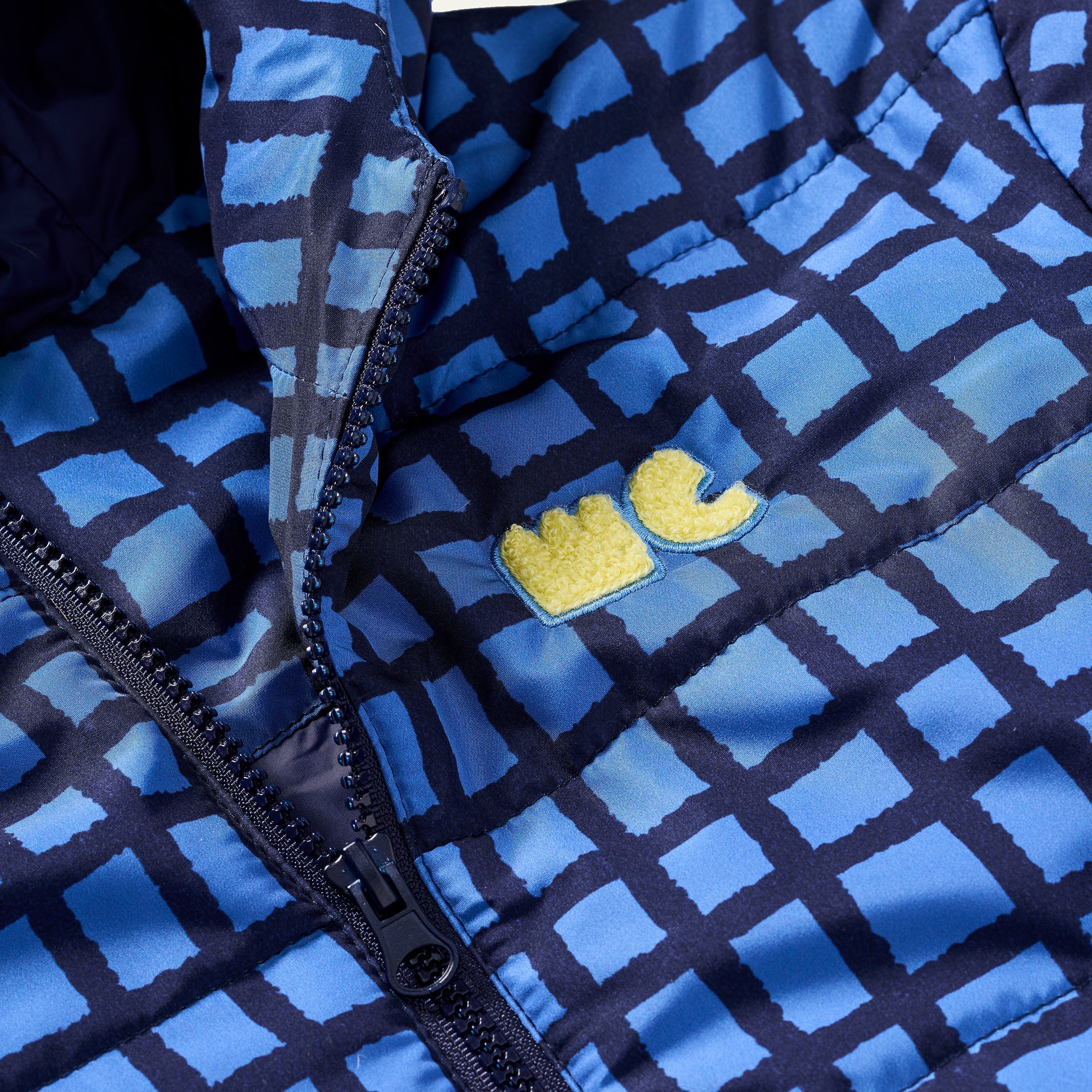 Close-up of the blue geometric grid print on the Mon Coeur kids' recycled puffer jacket