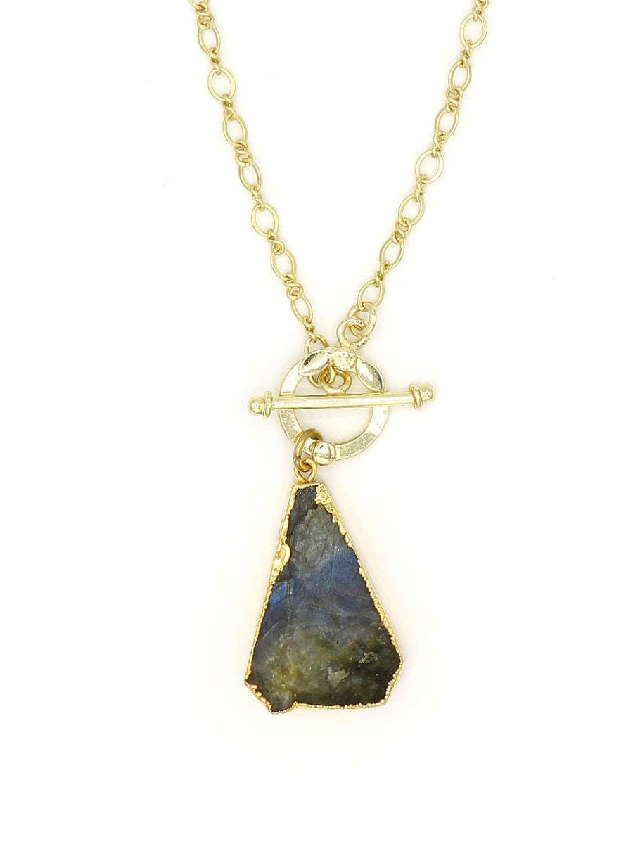 Woman wearing a raw labradorite triangle necklace on a brass-plated chain by Fair Anita
