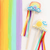 Colorful rainbow and sun-themed sticks with ribbons on a white background
