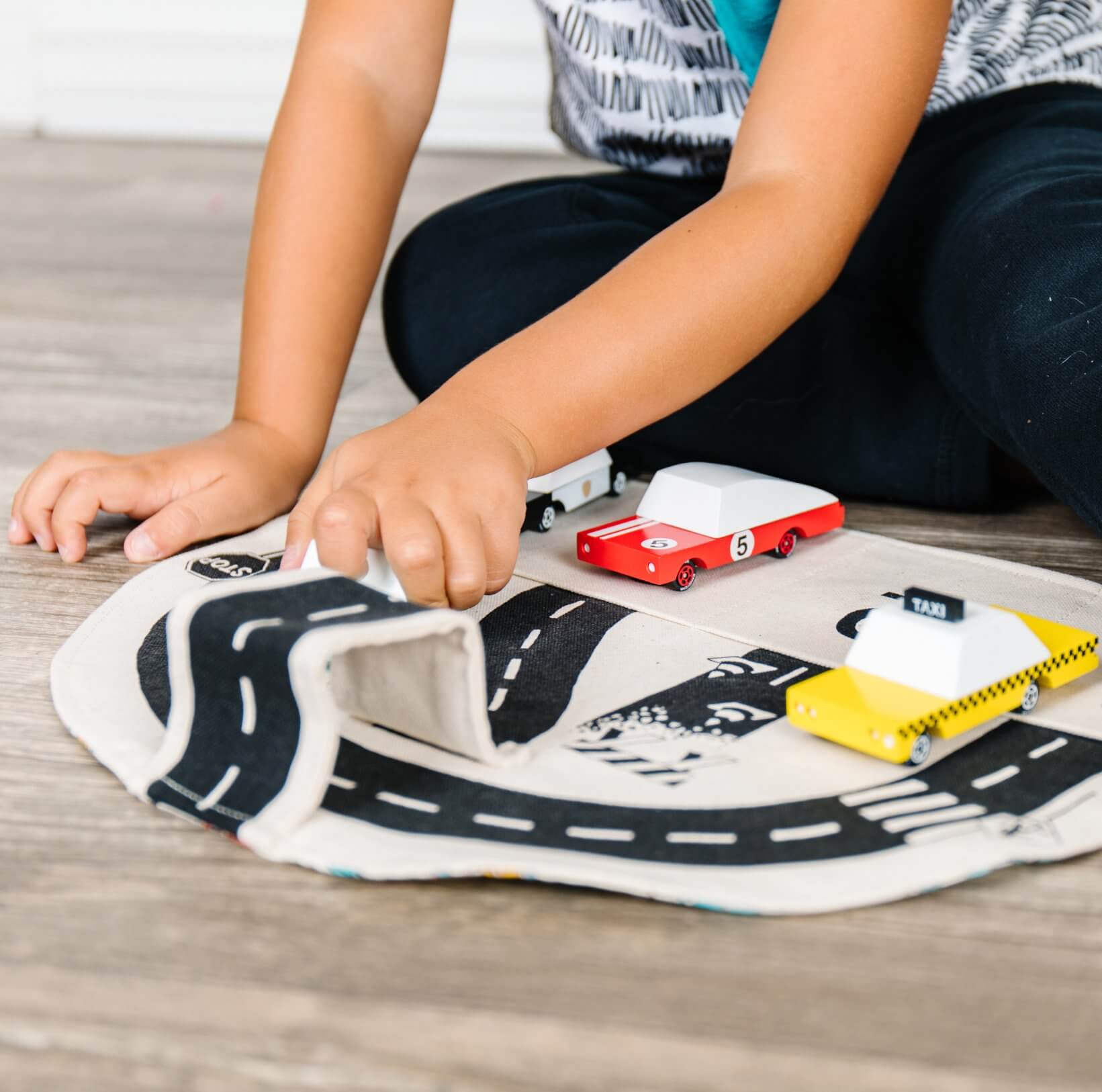 Child playing with toy cars on a road mat