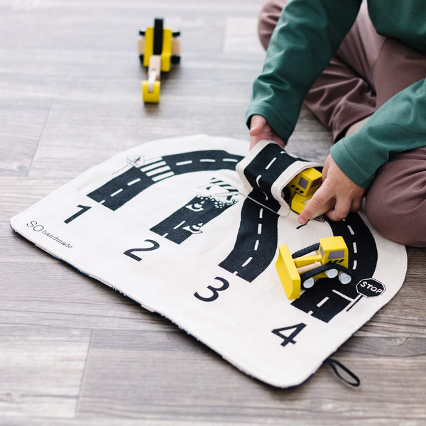 Child playing with toy cars on a road mat with numbers and road markings.