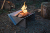 Metal fire pit with flames surrounded by nature
