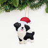 Stealing Santa's Hat Border Collie Ornament, a handmade felt black and white puppy wearing Santa's hat