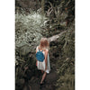 Person with a blue backpack walking through a forest