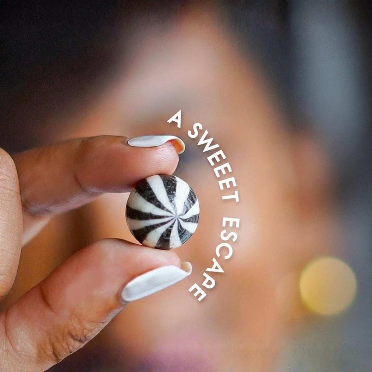 Hand holding a black and white striped candy with 'A Sweet Escape' text.