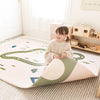 Child playing on a large play mat with road and nature designs in a room.