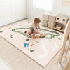 Child playing with wooden train on a large play mat in a room.