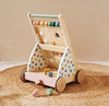 Wooden toy with colorful polka dot design on wheels, featuring various educational toys on a beige background.