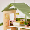 Wooden dollhouse with green roof and interior furniture on a white background