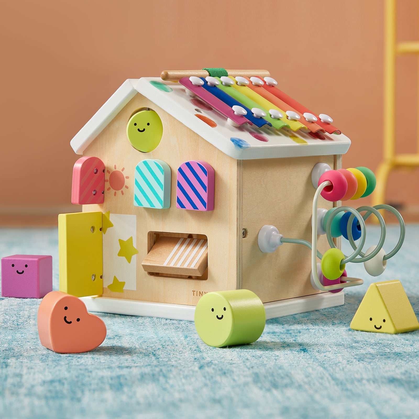Children's wooden toy with colorful shapes and a bead roller on a blue surface.