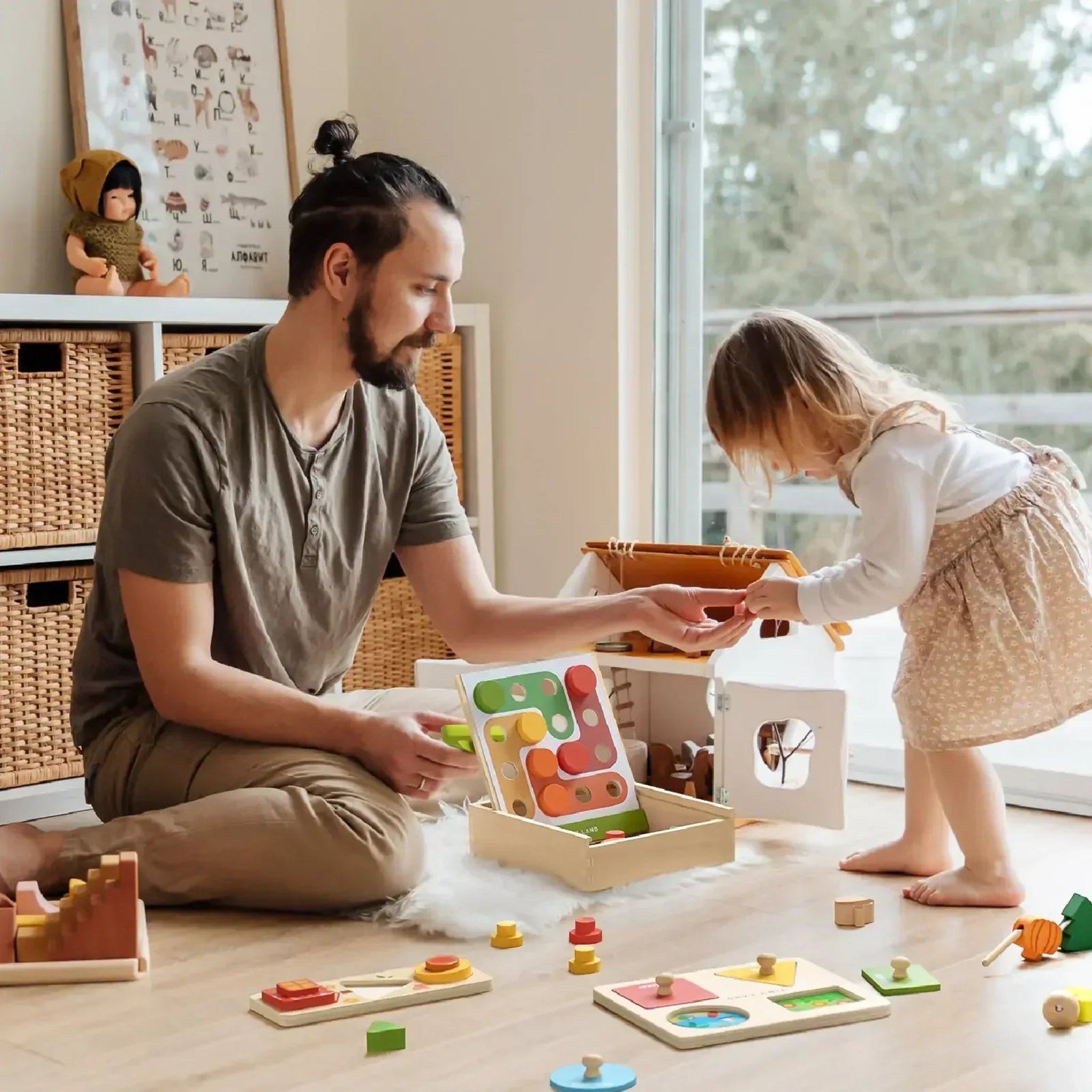 Man and child playing with colorful wooden toys on a light wood floor.