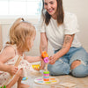 Woman and child playing with colorful wooden toys on a light-colored floor.