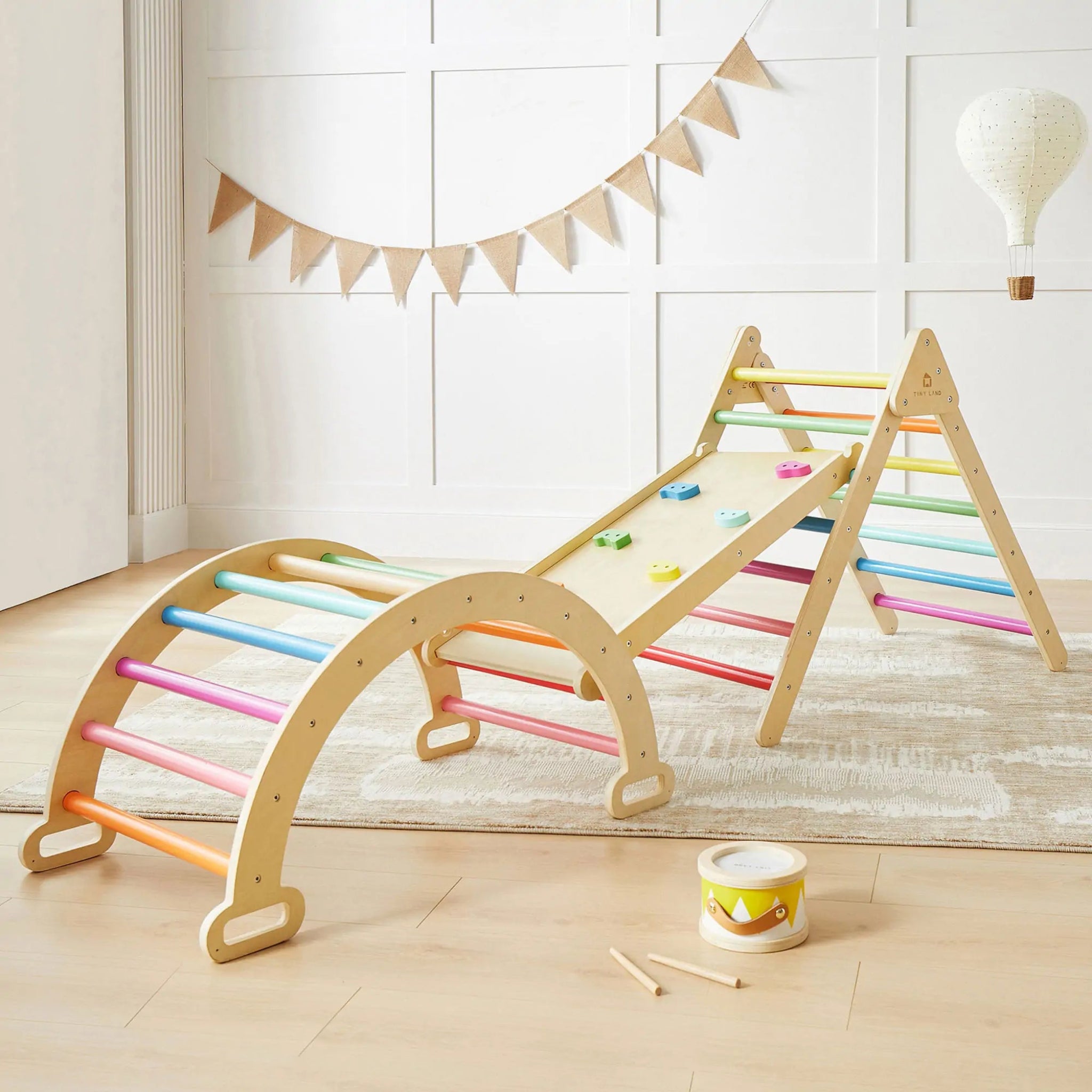 Children's play gym with colorful bars in a room with a white wall and wooden floor.