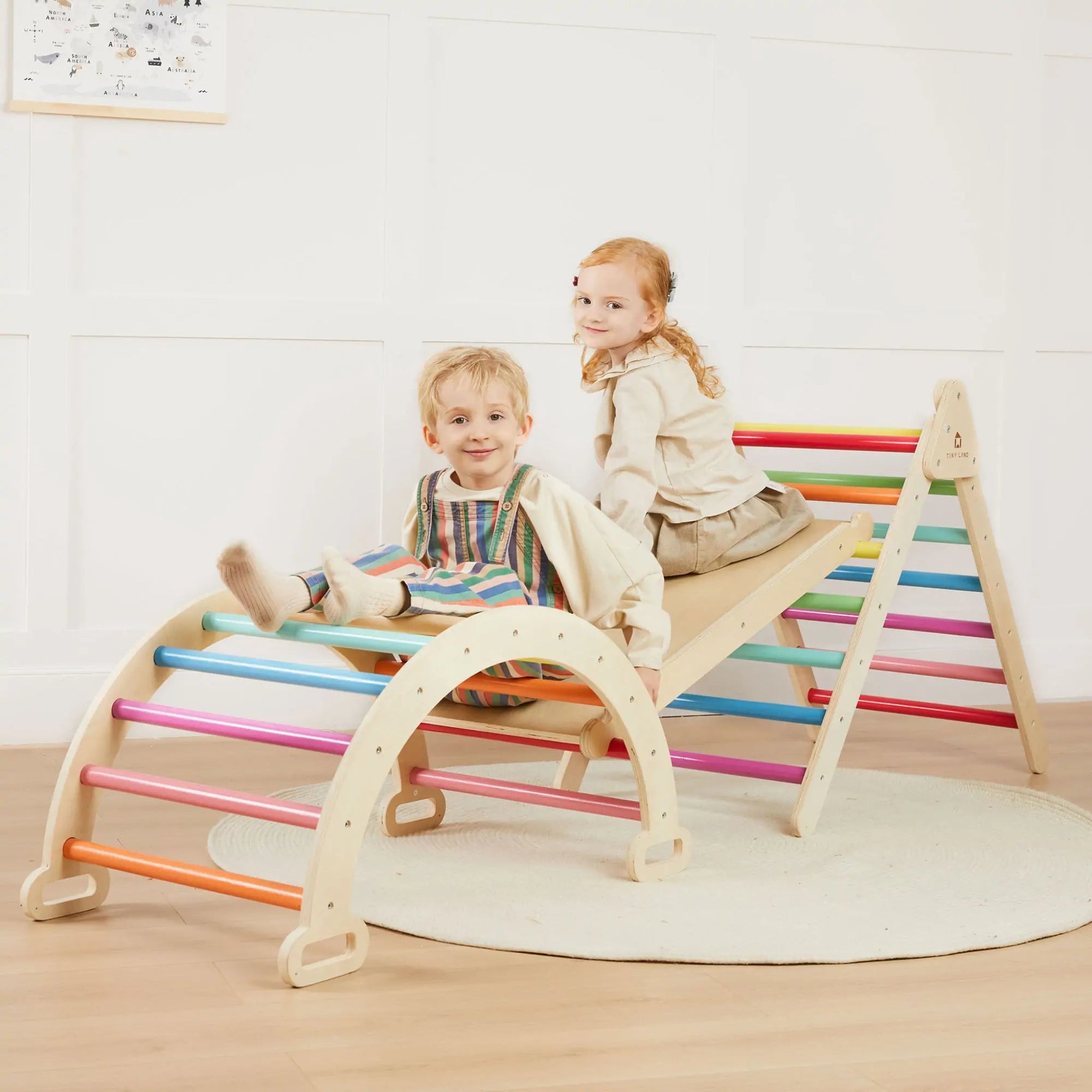 Two children playing on a colorful wooden seesaw indoors.