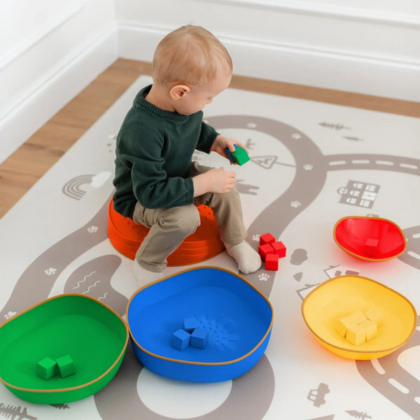 Child playing with colorful toy bins on a road map play mat