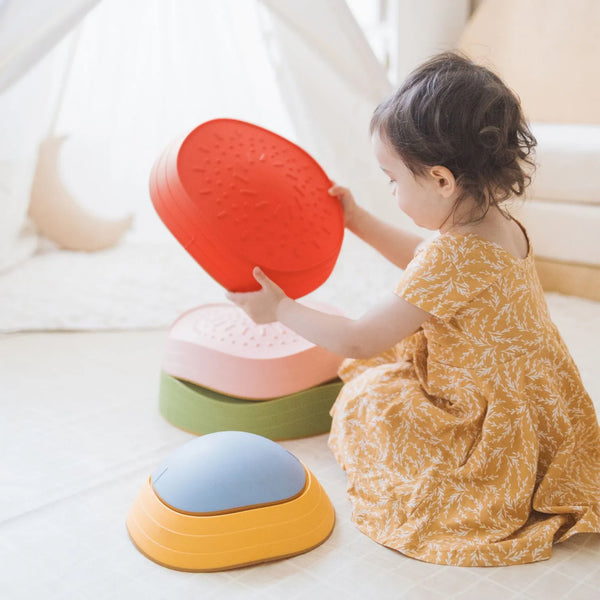 Child playing with colorful stacking toys on a light surface
