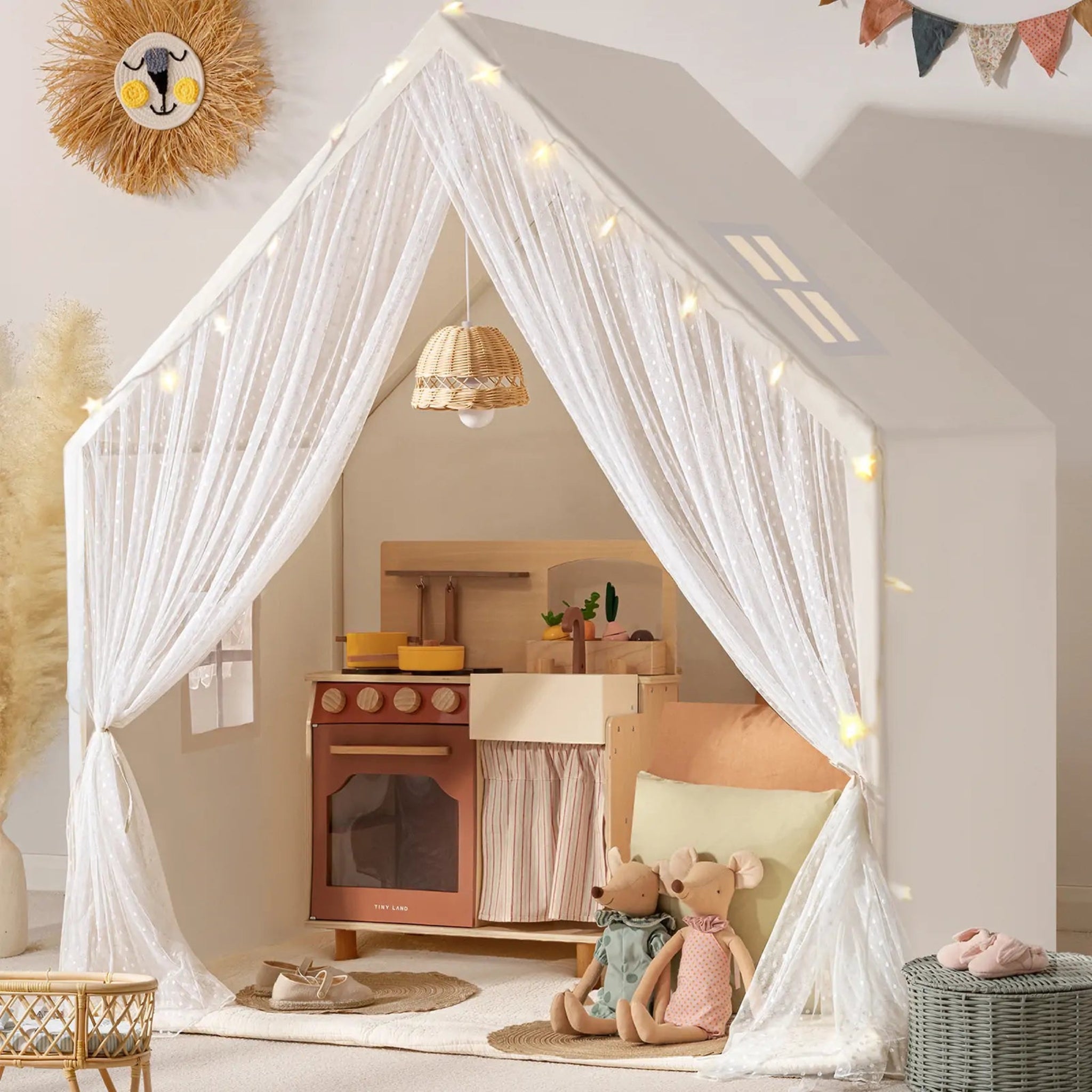 Children's play area with a toy kitchen and teddy bears, draped with white curtains.