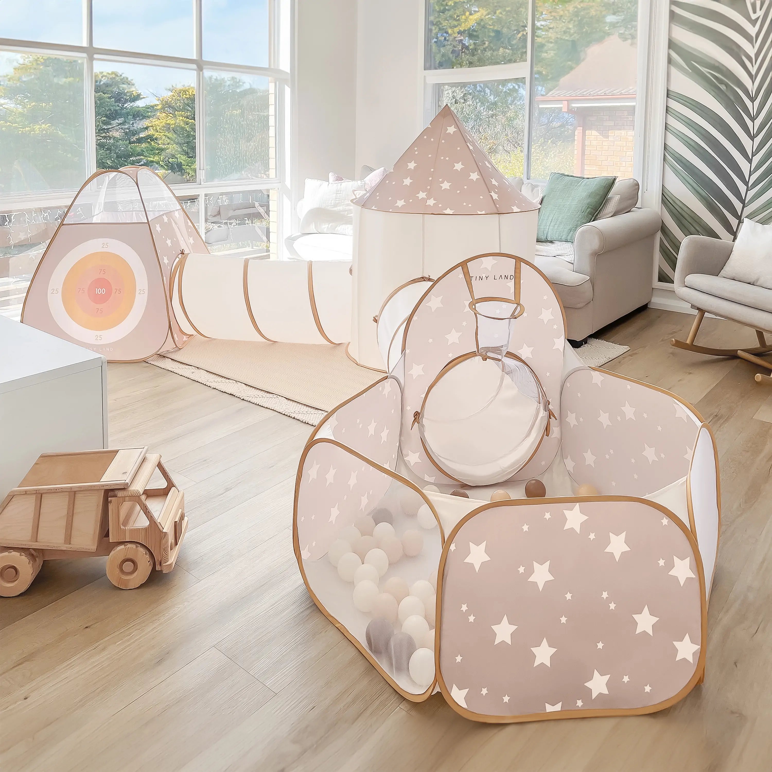 Children's play area with a star-patterned play tent and tunnel in a bright room.