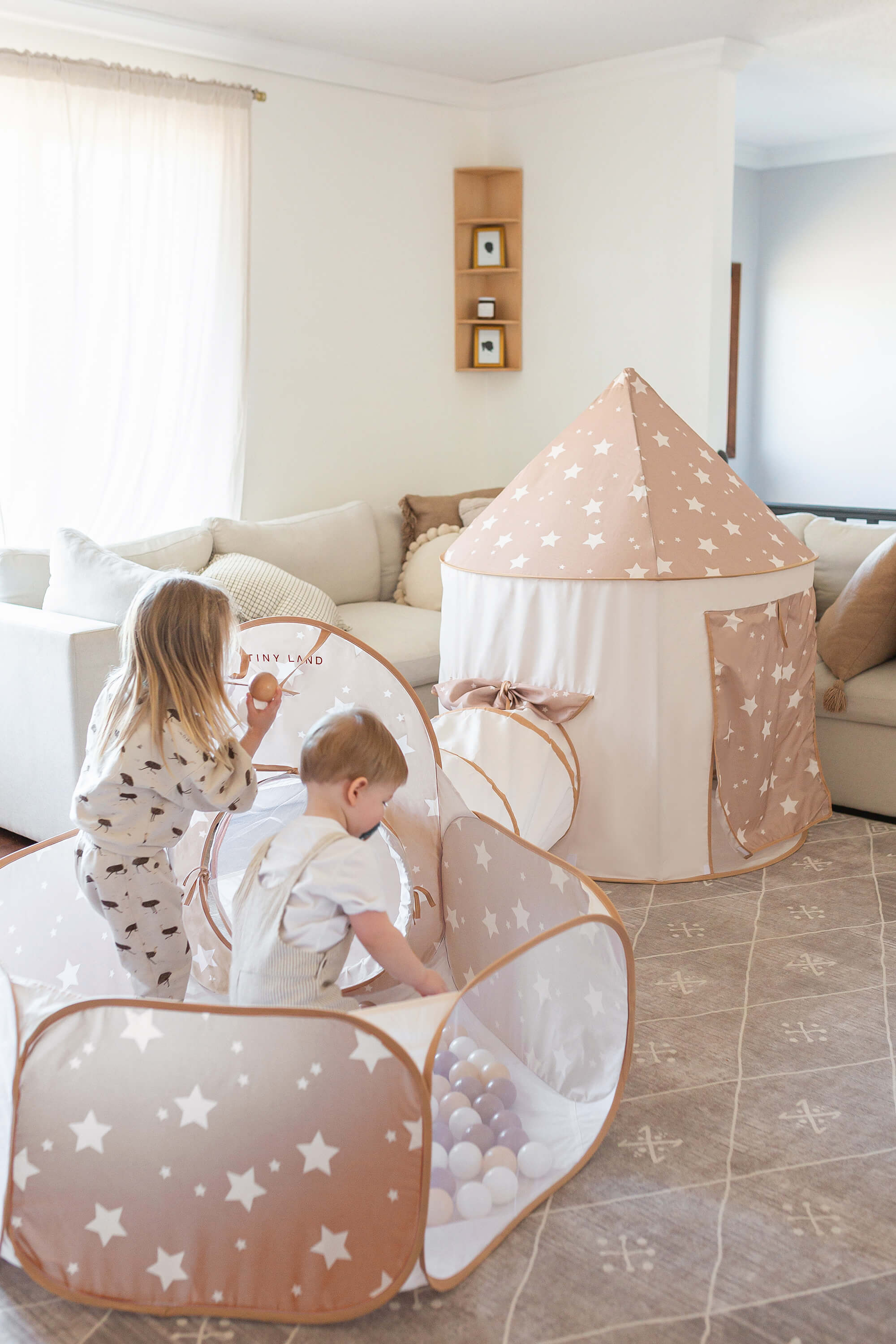 Children playing inside a star-patterned play tent in a living room.