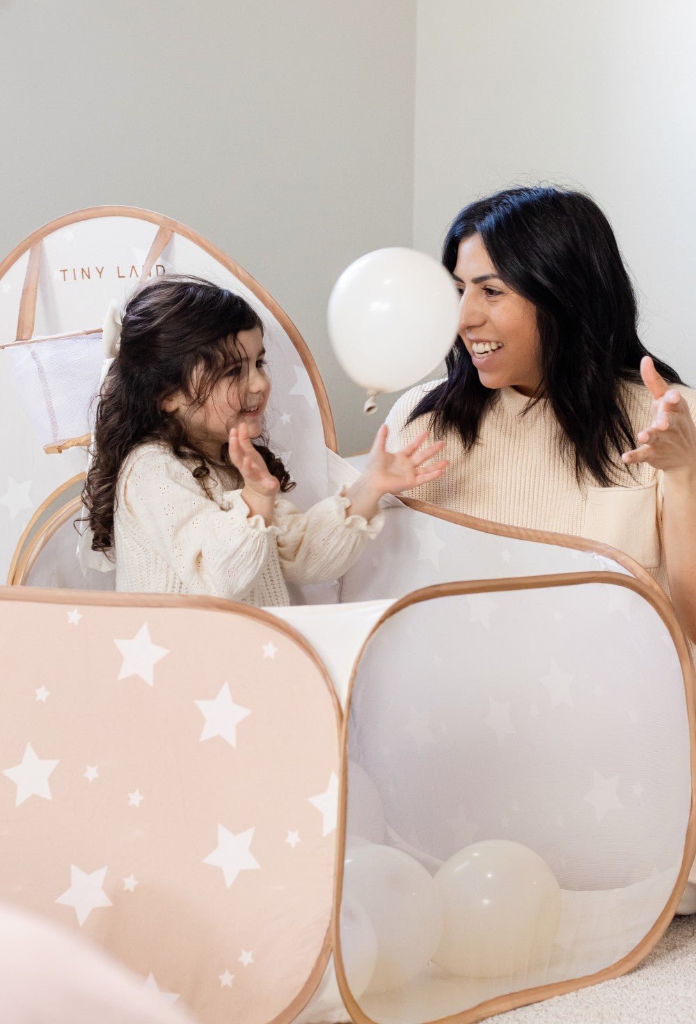 Woman and child playing with a star-patterned playpen.