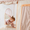 Child playing with a pink tent in a room with white walls and a window.