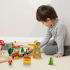Child playing with wooden train set on a light-colored floor.