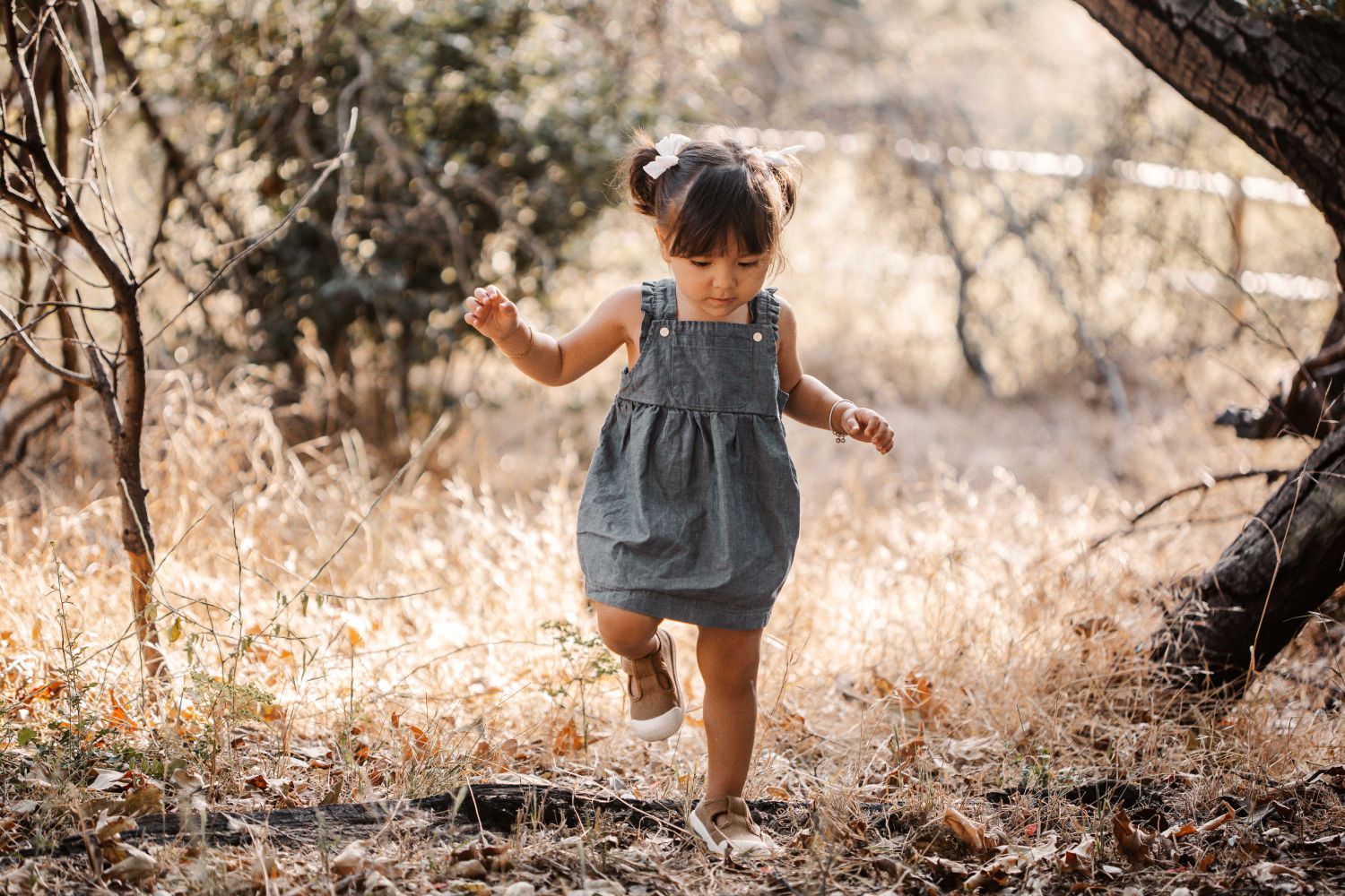 Front view of Apple Park organic chambray overall dress with ruffled cross-back straps and front pocket