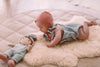 Close-up of baby in teal organic muslin romper with ruffled flutter sleeves and snap back closure
