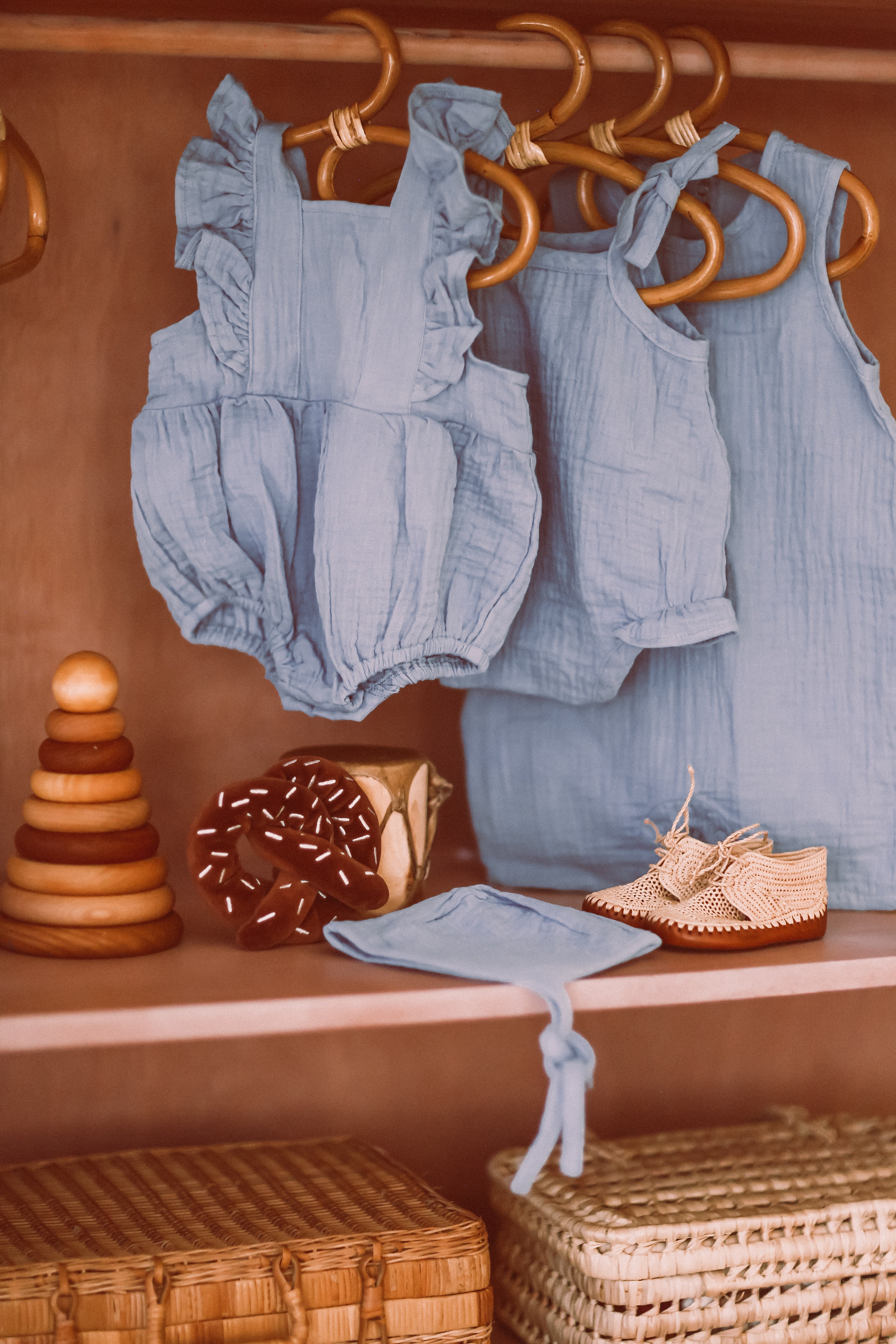 Apple Park blue muslin flutter sleeve romper styled with matching romper with ties, coverall, bonnet and pretzel rattle