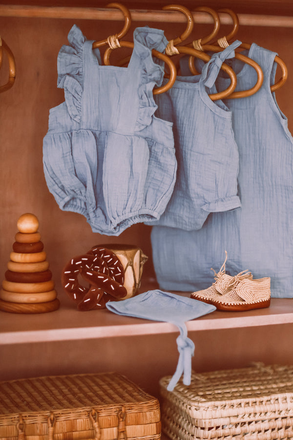 Apple Park blue muslin flutter sleeve romper styled with matching romper with ties, coverall, bonnet and pretzel rattle