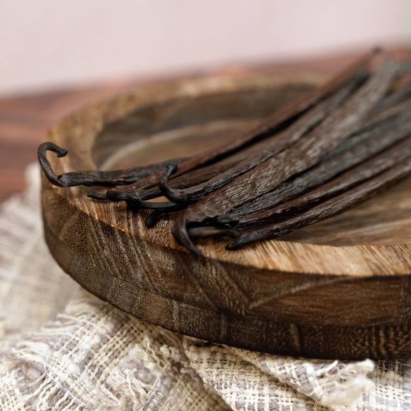 Vanilla beans on a wooden cutting board with a soft background
