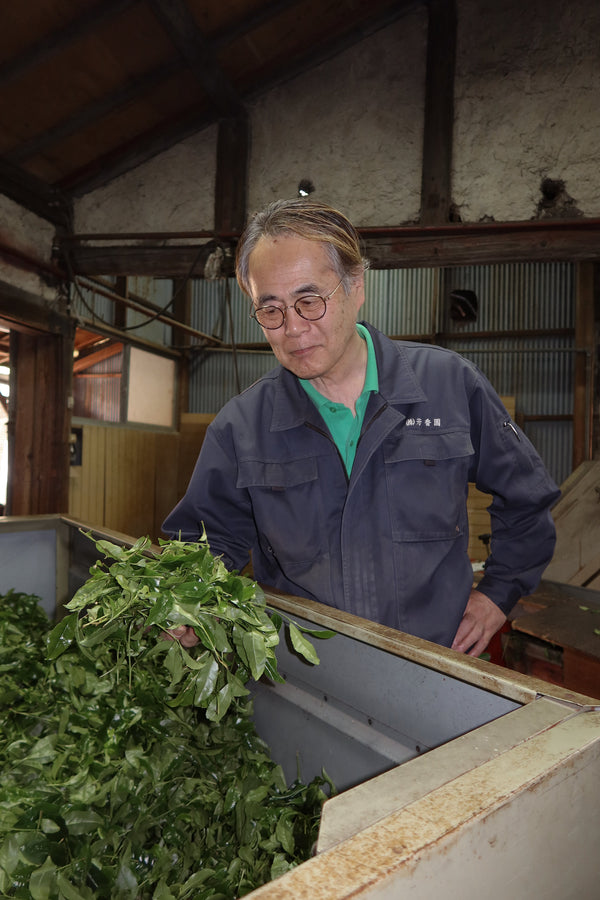 Man working with green leaves in a traditional setting