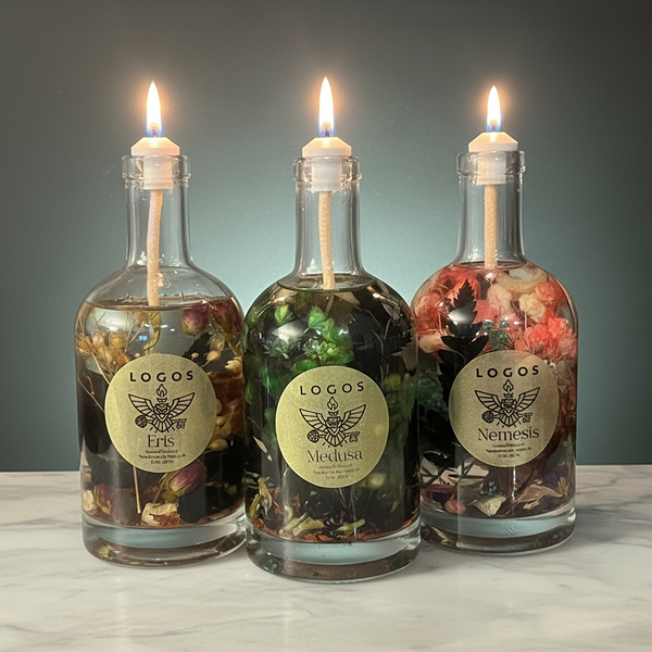 Three lit candles in glass bottles with decorative elements and 'Logos' branding on a neutral background.