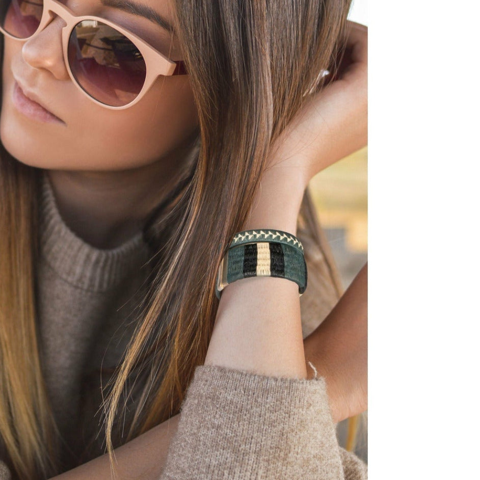 Woman wearing striped woven palm leaf cuff bracelet styled as a gift accessory