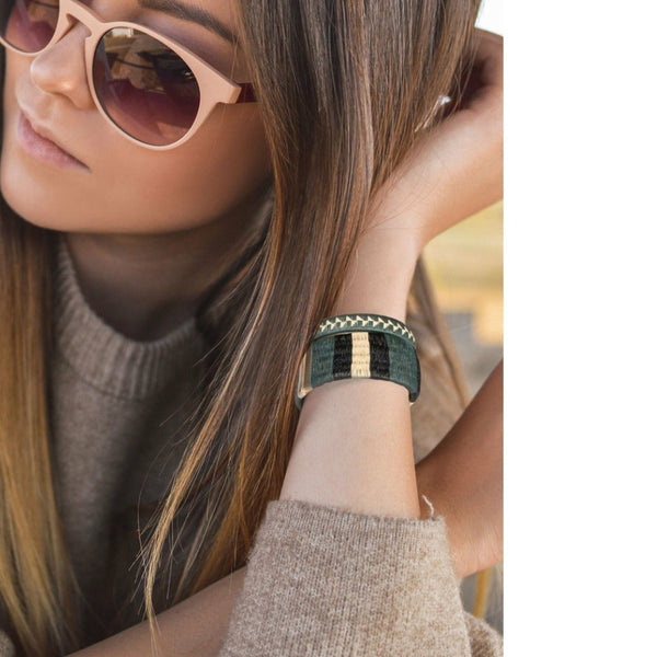 Woman wearing striped woven palm leaf cuff bracelet styled as a gift accessory