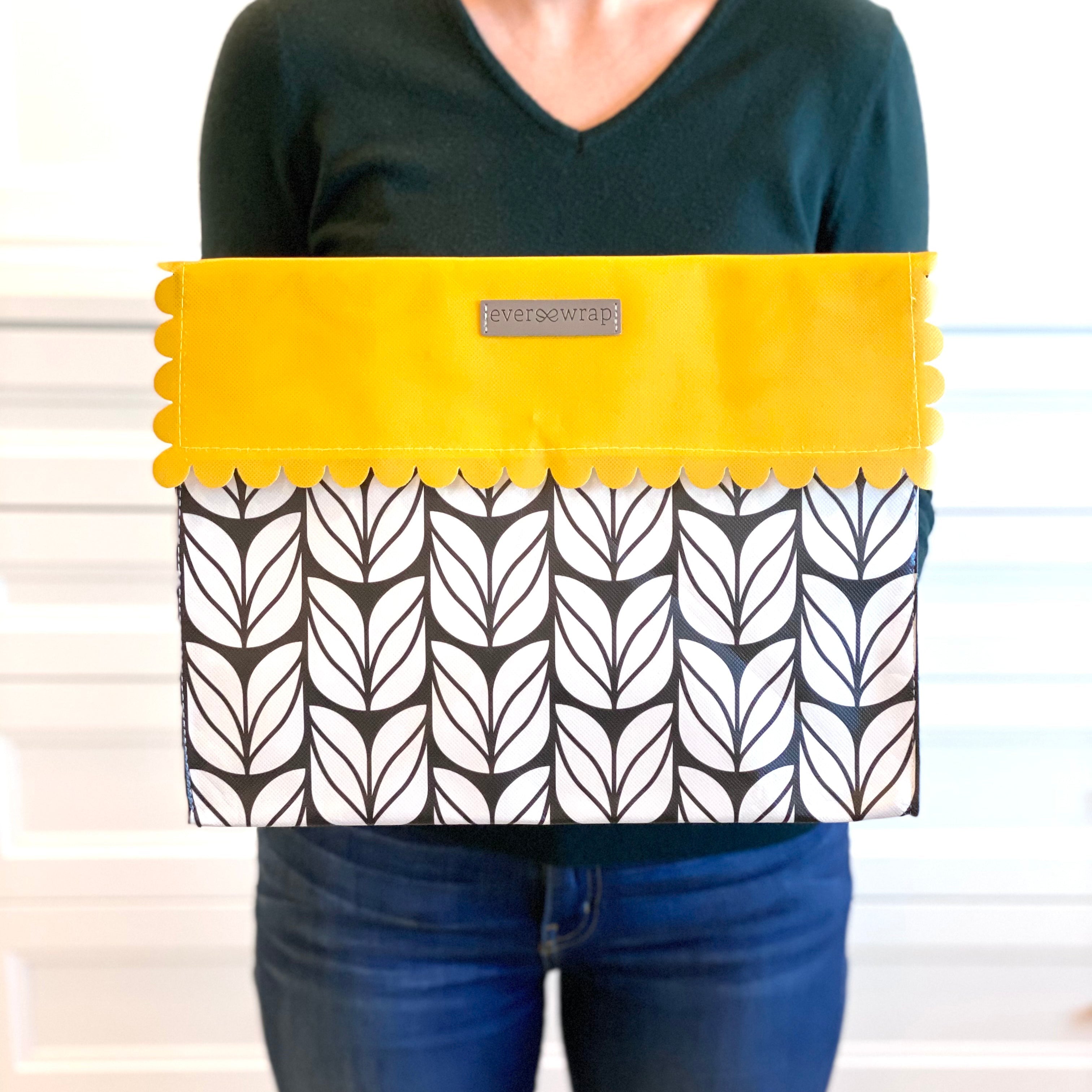 Flat-lay of EverWrap EverEnvelope foldable reusable gift wrap bag in black, white and marigold