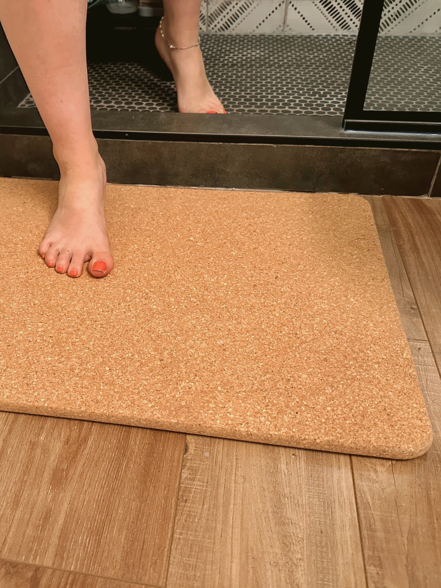 Person stepping onto a cork mat from a shower area.