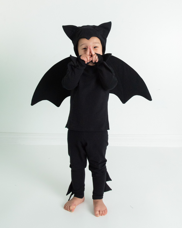 Child wearing a black bat costume on a white background