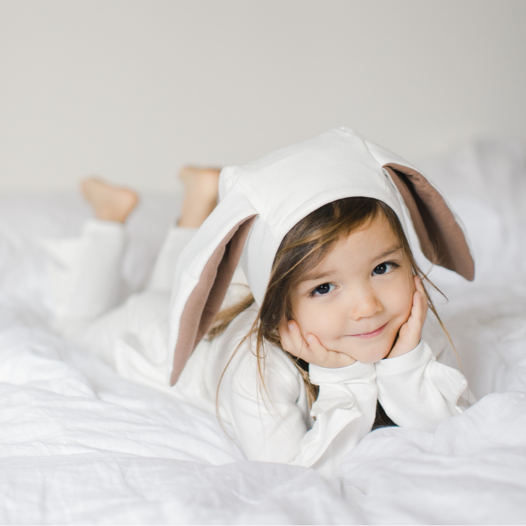 Child wearing a bunny costume lying on a white bed