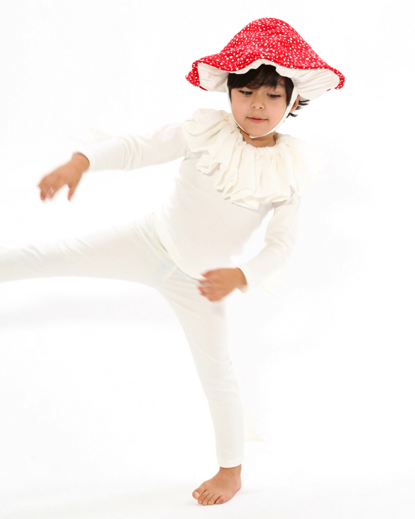 Child wearing a white outfit with a red floral hat on a white background