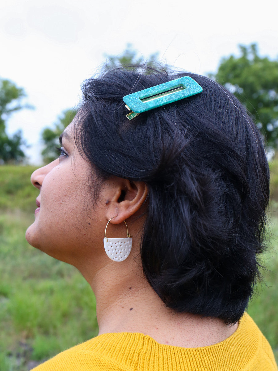 Upcycled bone half moon hoop earrings styled with a resin hair clip, worn as an everyday eco-friendly accessory