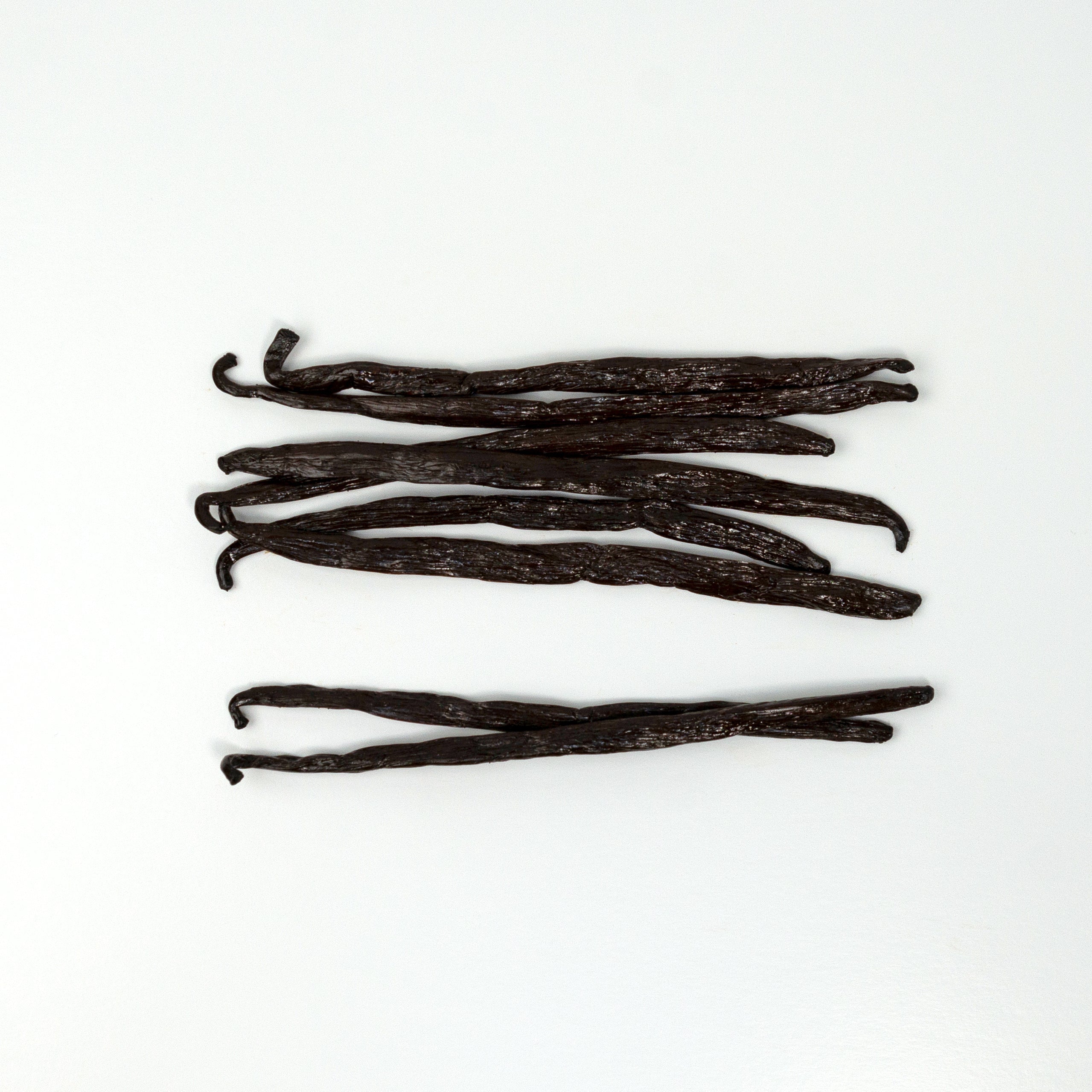 Vanilla beans arranged on a white background