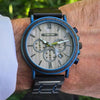 Wristwatch with a detailed face on a person's wrist, blurred green background