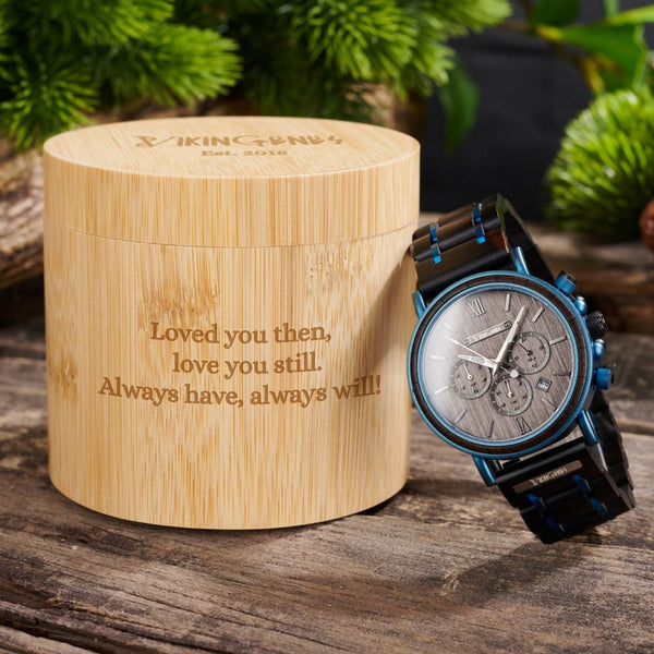Wooden watch box with engraved message and a wooden watch on a wooden surface.